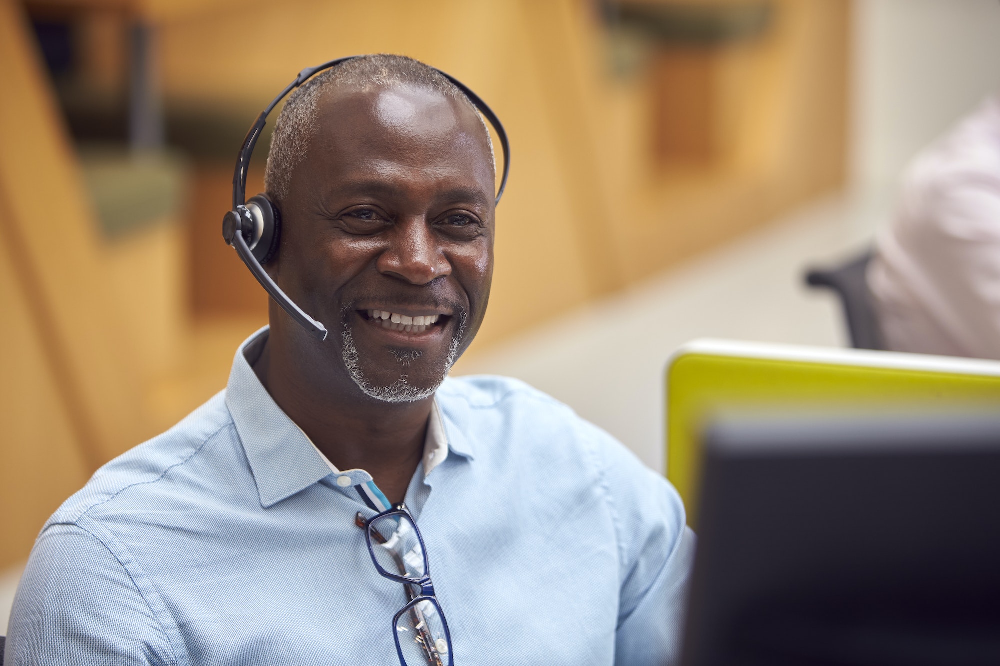Portrait Of Mature Businessman Wearing Phone Headset Talking To Caller In Customer Services Centre